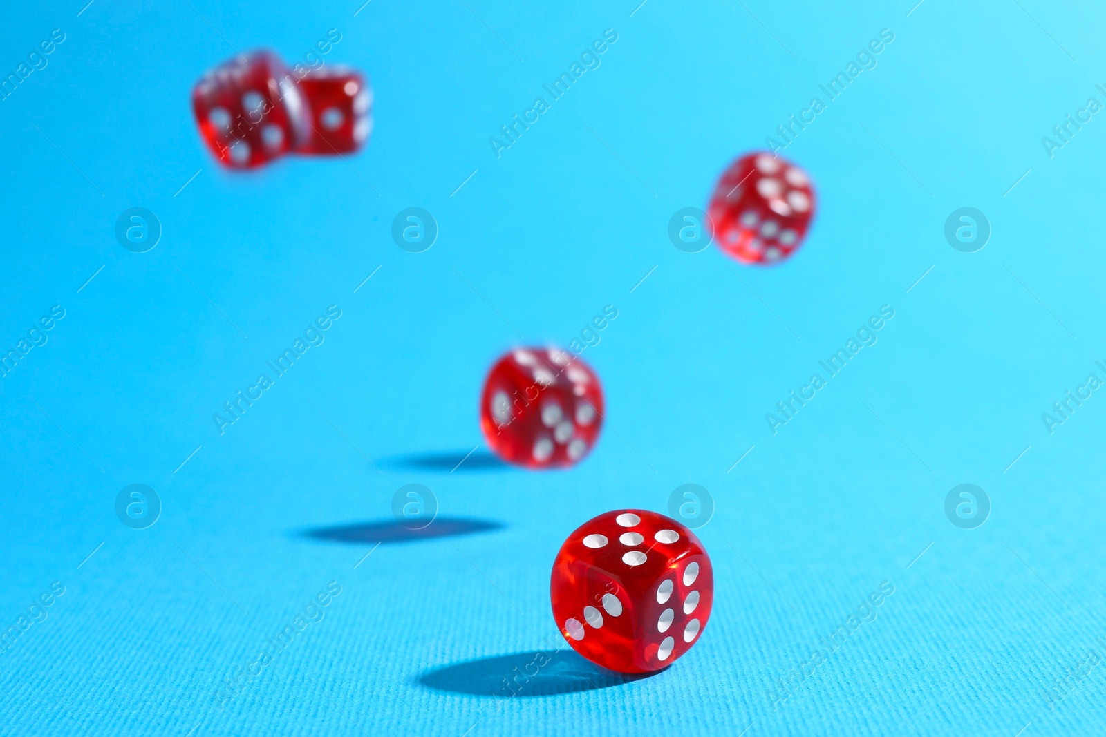 Photo of Many red game dices falling on light blue background