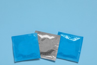 Condom packages on light blue background, flat lay and space for text. Safe sex