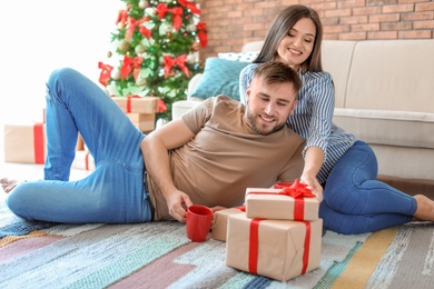 Happy young couple with Christmas gifts at home