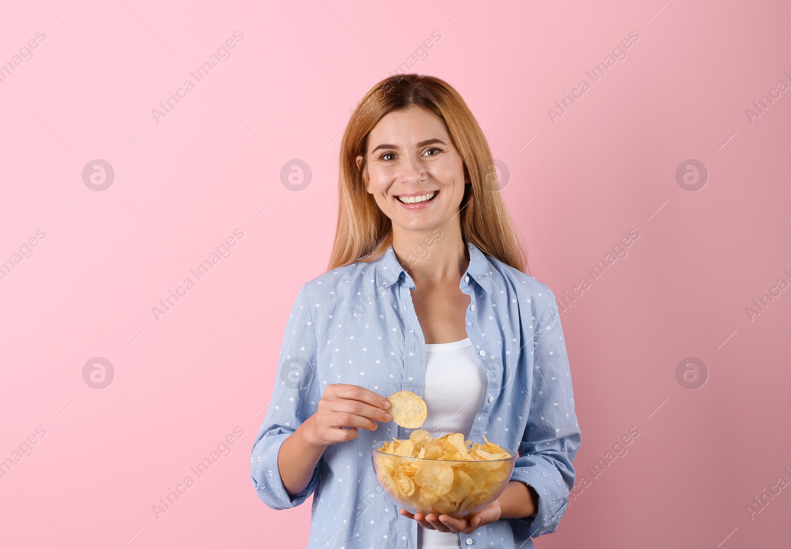 Photo of Woman with bowl of potato chips on color background