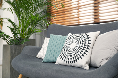 Photo of Stylish decorative pillows on grey couch indoors, closeup