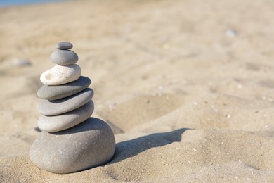 Stack of stones on sandy beach, space for text