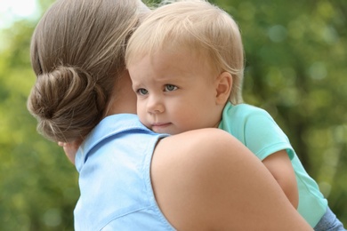 Young mother with her cute child in green park