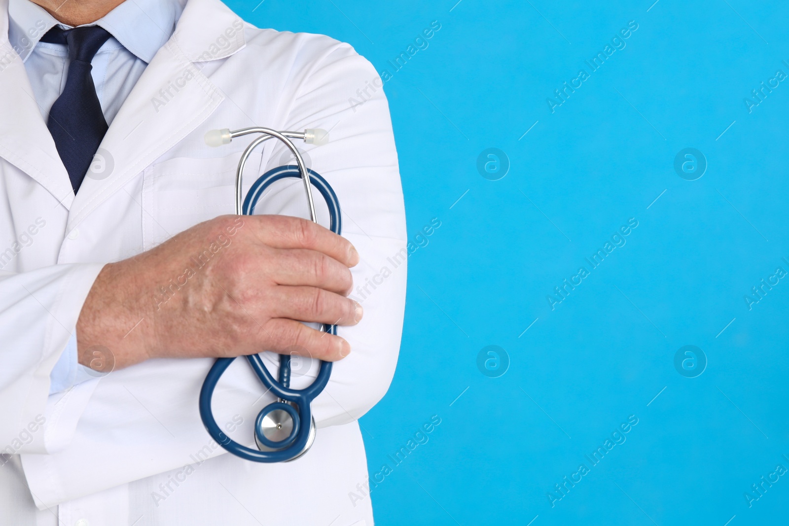 Photo of Senior doctor with stethoscope on blue background, closeup, space for text