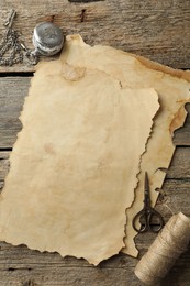 Sheet of old parchment paper, scissors, rope and pocket chain clock on wooden table, flat lay