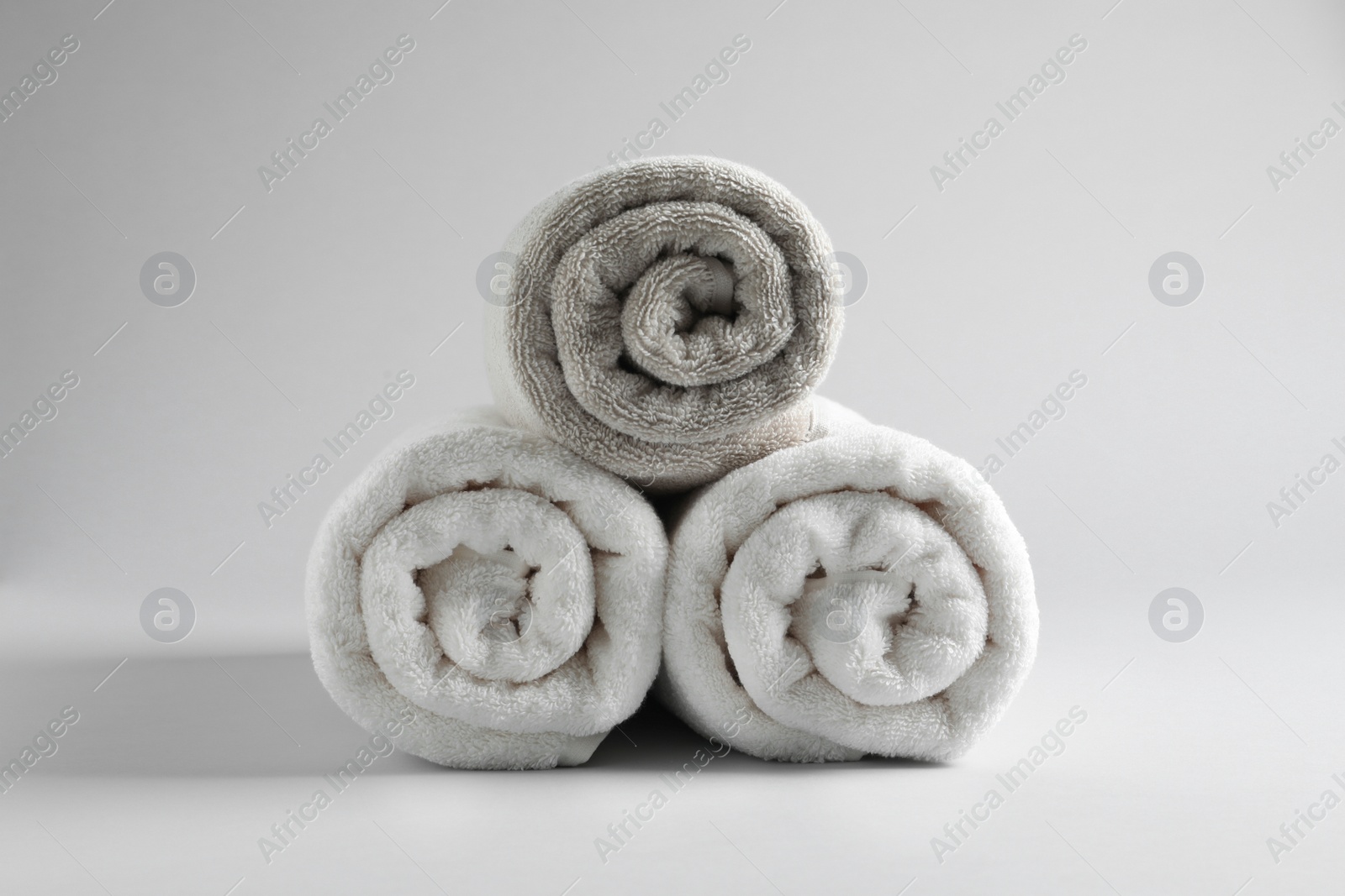 Photo of Fresh soft rolled towels on light background