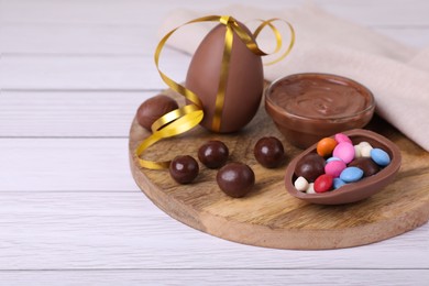 Photo of Composition with delicious chocolate eggs and candies on white wooden table. Space for text