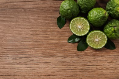 Fresh ripe bergamot fruits with green leaves on wooden table, flat lay. Space for text