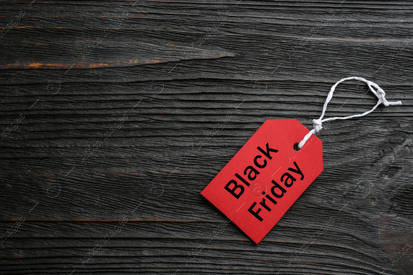 Photo of Top view of blank red tag on dark wooden background, space for text. Black Friday concept