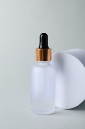 Photo of Bottle with cosmetic serum on light grey background