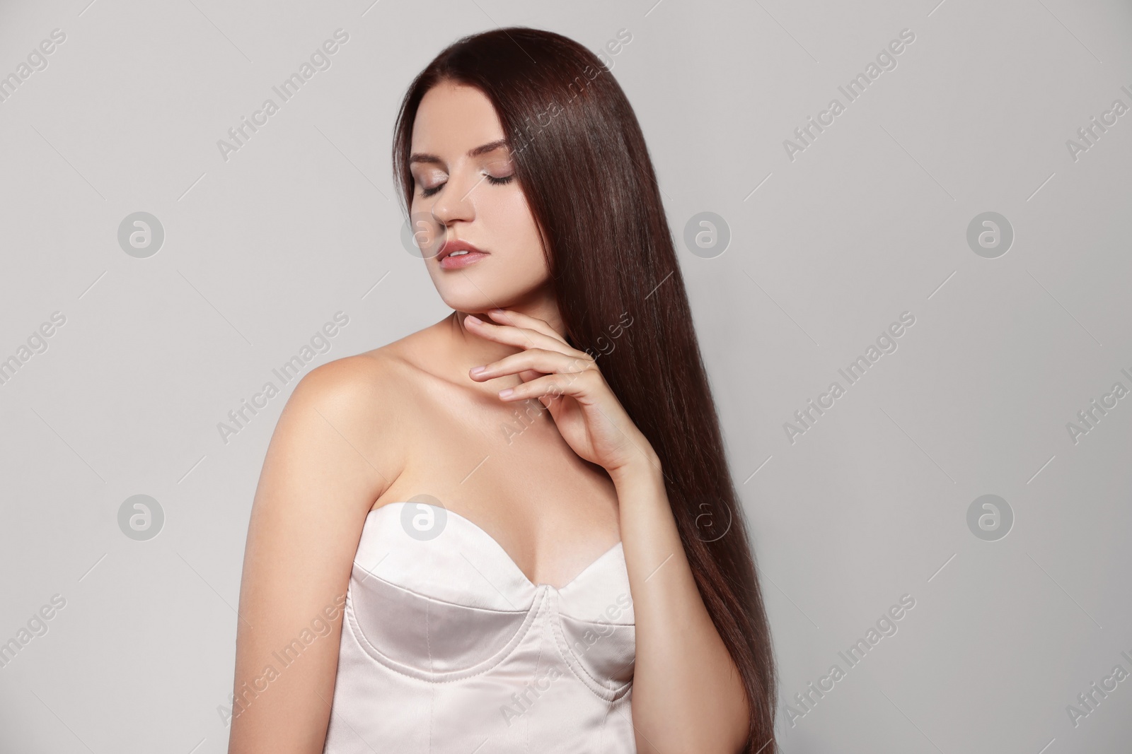 Photo of Portrait of beautiful young woman with healthy strong hair on light gray background, space for text