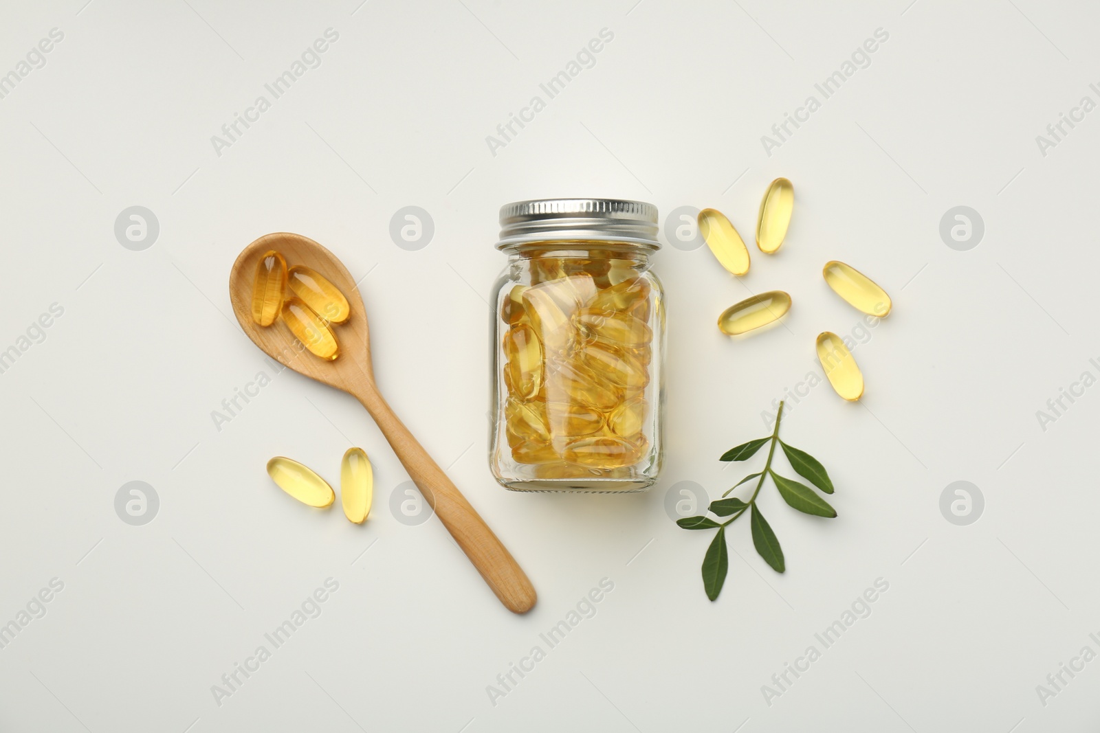 Photo of Bottle, vitamin capsules, spoon and leaves on white background, flat lay