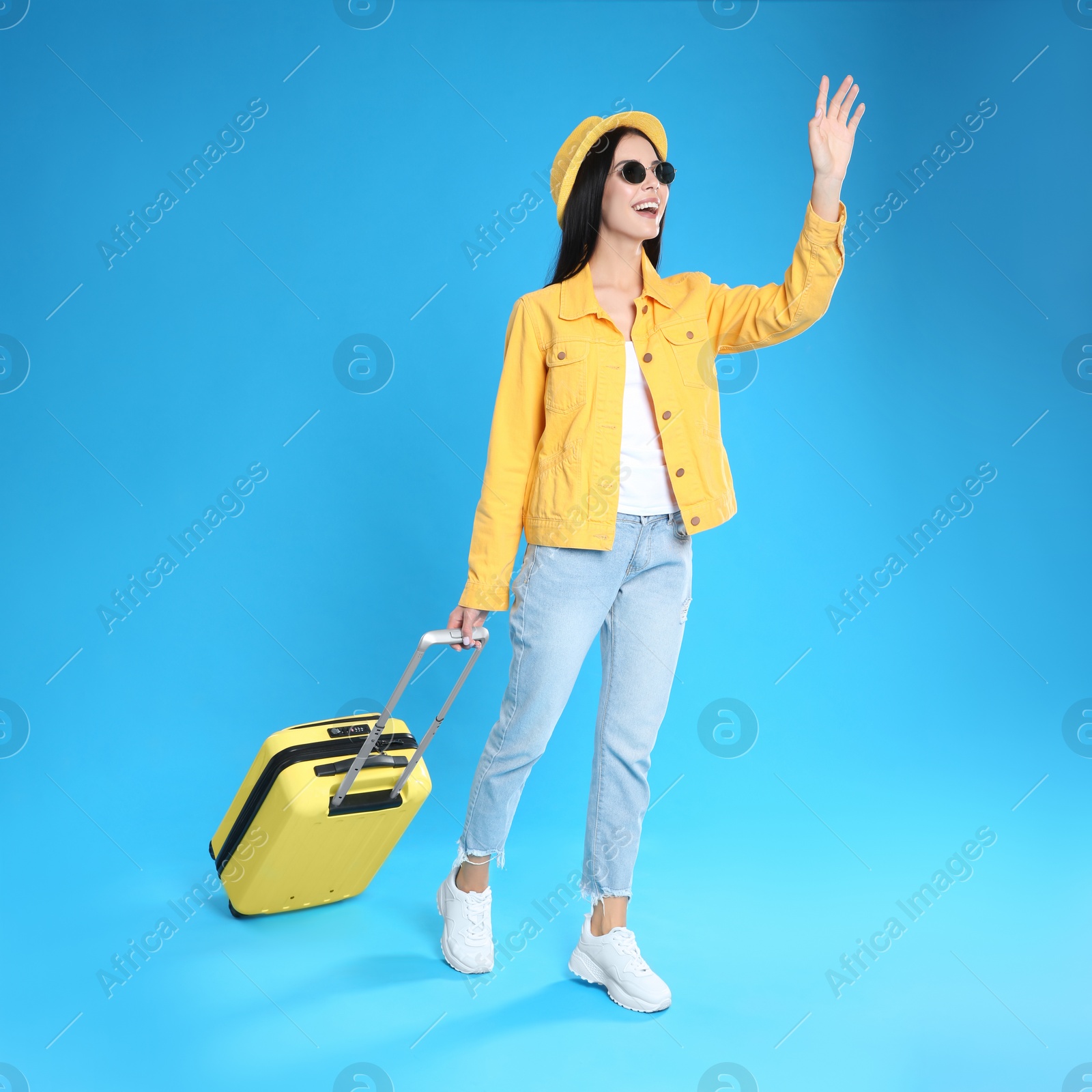 Photo of Beautiful woman with suitcase for summer trip on blue background. Vacation travel