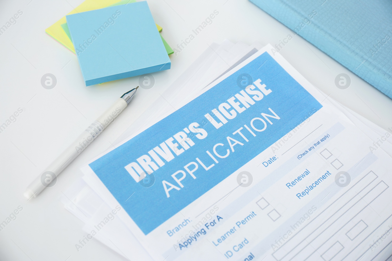 Photo of Driver's license application form and stationery on white table