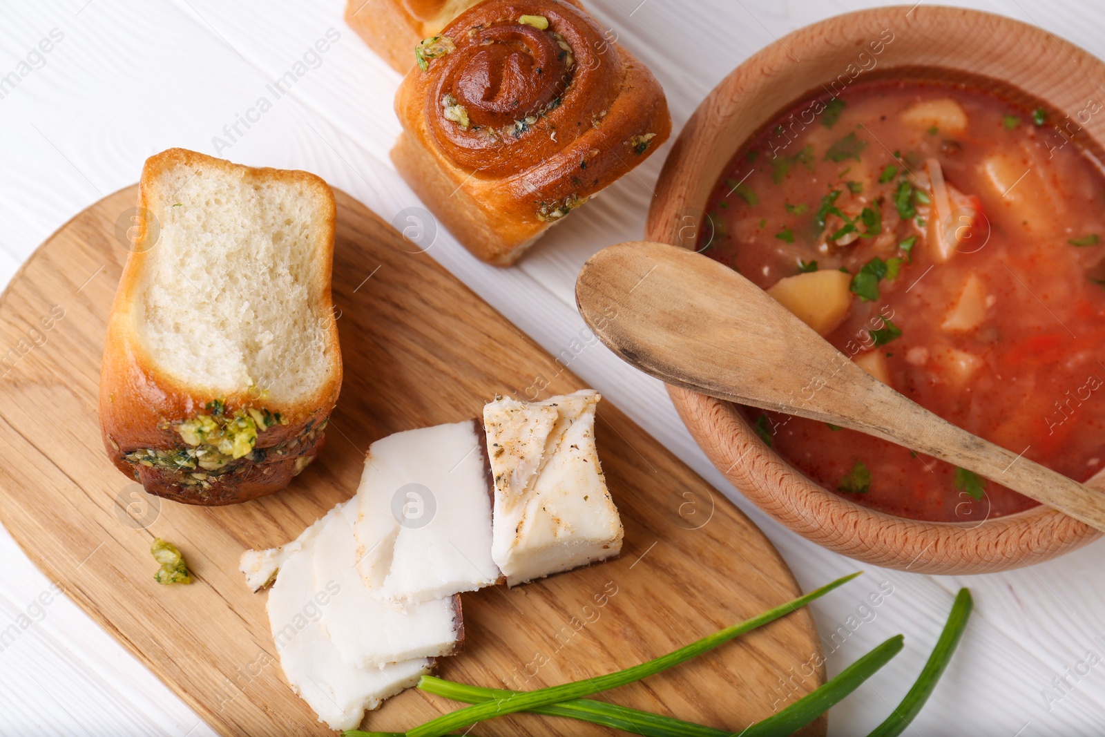 Photo of Delicious borsch served with pampushky and salo on white wooden table, flat lay. Traditional Ukrainian cuisine