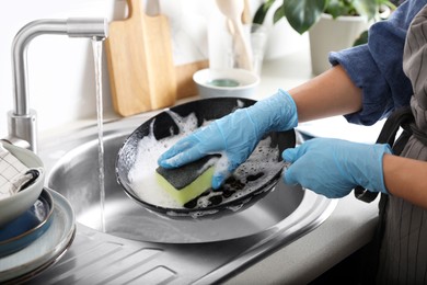 Photo of Woman washing dirty frying pan in sink indoors, closeup