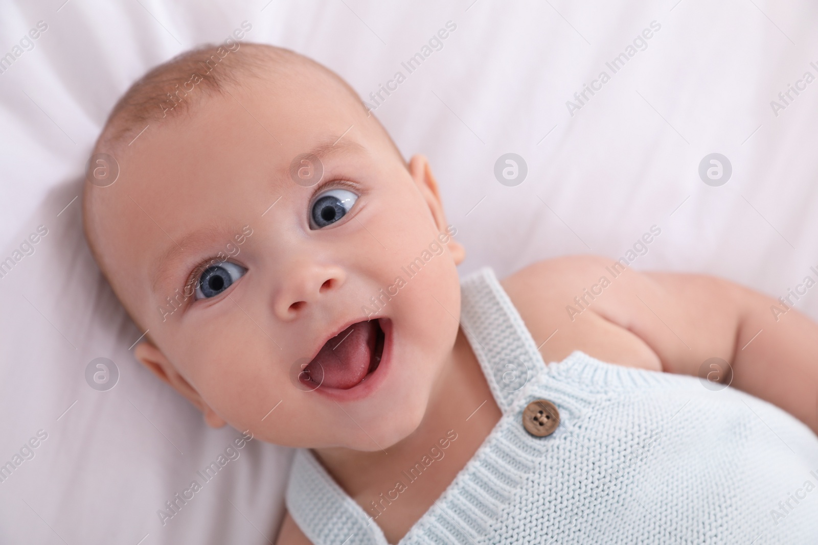 Photo of Cute little baby lying on white blanket, top view