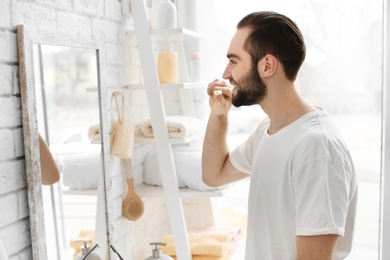 Young man brushing his teeth in bathroom