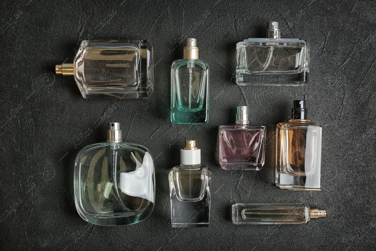 Photo of Perfume bottles on dark background, flat lay