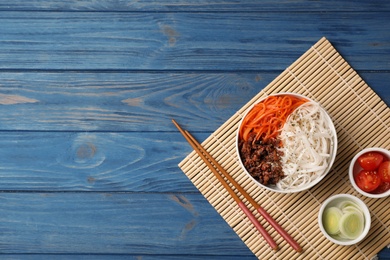 Photo of Flat lay composition with rice noodles and vegetables on wooden background. Space for text