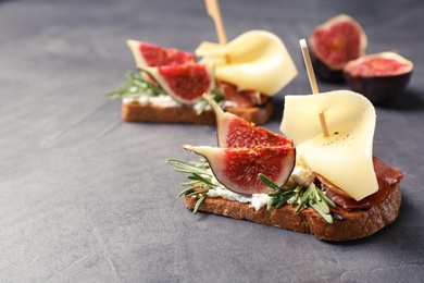 Photo of Sandwich with ripe fig, prosciutto and cheese on grey background, closeup