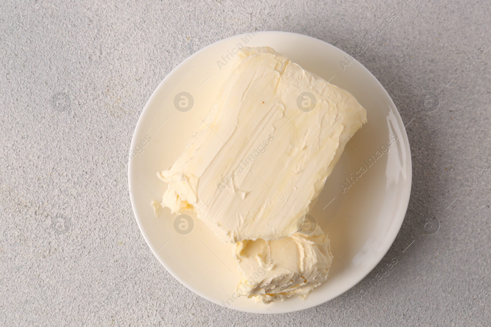 Photo of Plate with tasty homemade butter on white textured table, top view