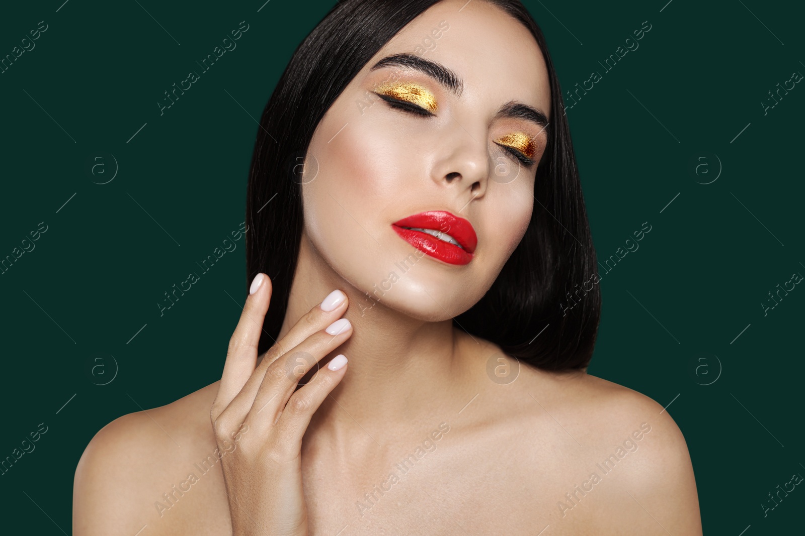 Image of Young woman with beautiful gold eyeshadow and red lips on dark green background