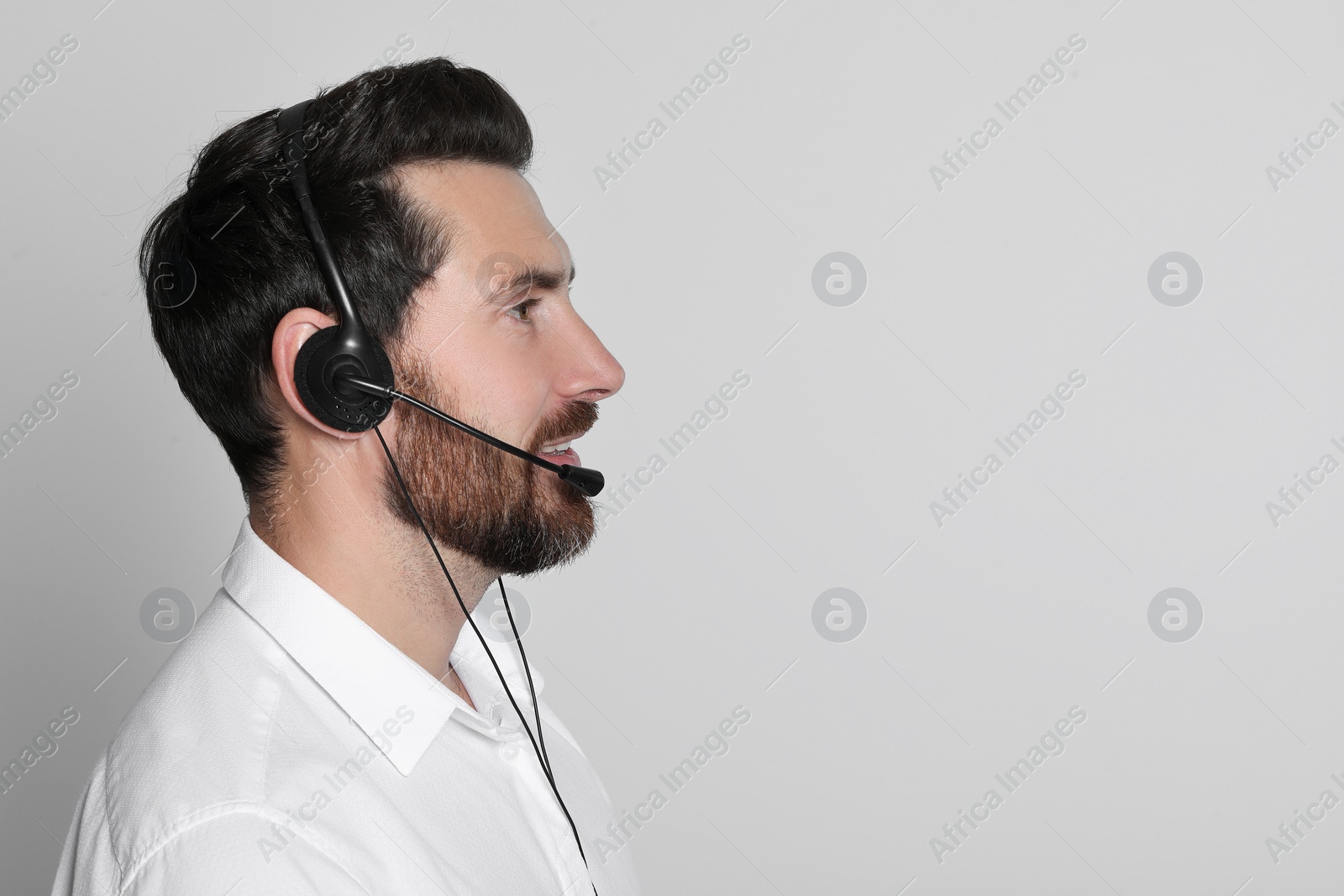 Photo of Hotline operator with headset on light grey background, space for text