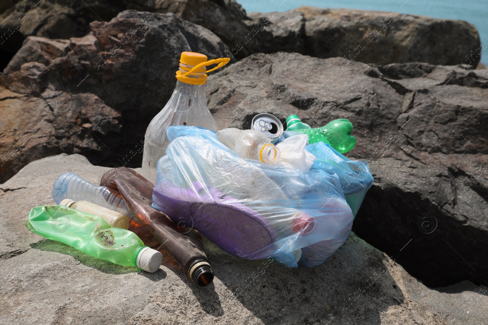 Photo of Garbage on stones near sea. Environmental Pollution concept