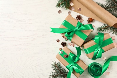 Photo of Flat lay composition with Christmas gift boxes and fir branches on white wooden background. Space for text