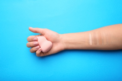 Photo of Woman testing different shades of liquid foundation on her hand against color background, closeup
