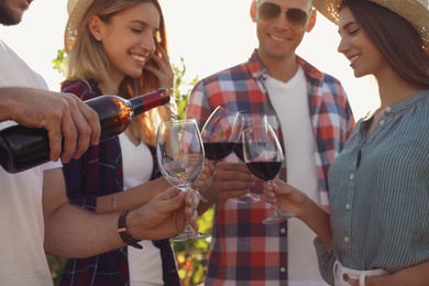 Photo of Friends tasting red wine at vineyard, focus on hands