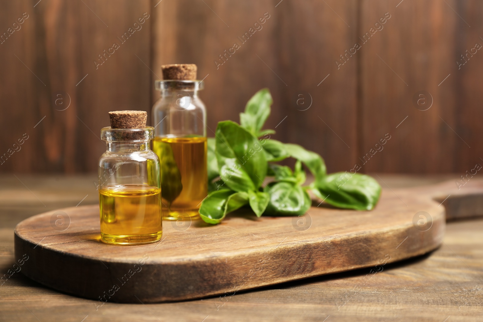 Photo of Wooden board with basil oil in glass bottles