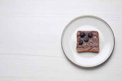 Toast with tasty nut butter, blueberries and nuts on white wooden table, top view. Space for text