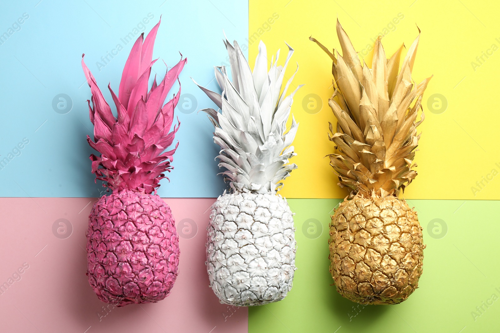 Photo of Pink, white and golden pineapples on color background, flat lay. Creative concept
