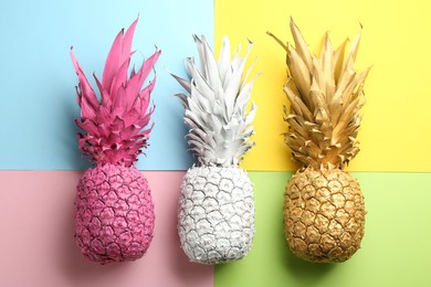 Pink, white and golden pineapples on color background, flat lay. Creative concept