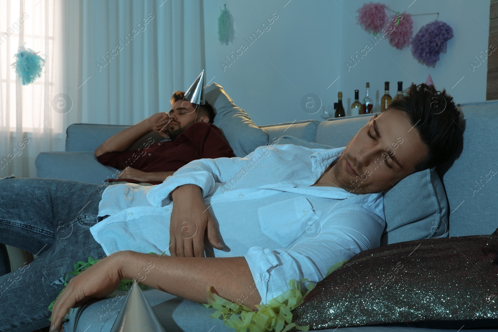 Photo of Drunk men sleeping on sofa in room after party