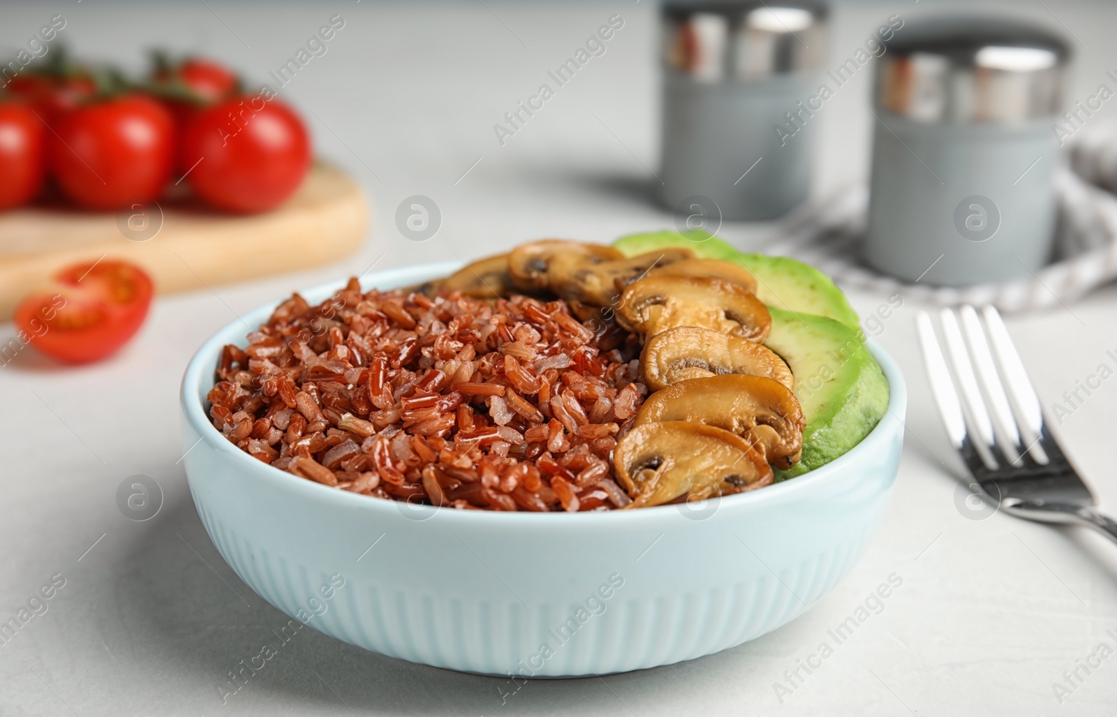 Photo of Bowl of brown rice with mushrooms and avocado on table, closeup