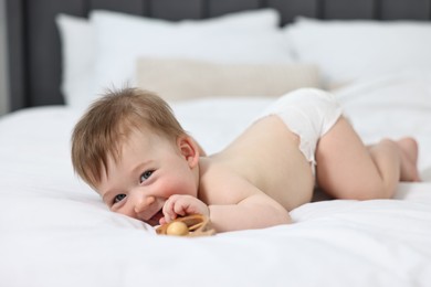Cute baby boy with rattle on bed at home