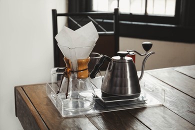 Photo of Coffee maker, grinder and kettle on wooden table in cafe