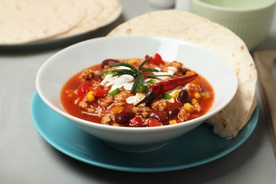 Plate with tasty chili con carne served on gray table