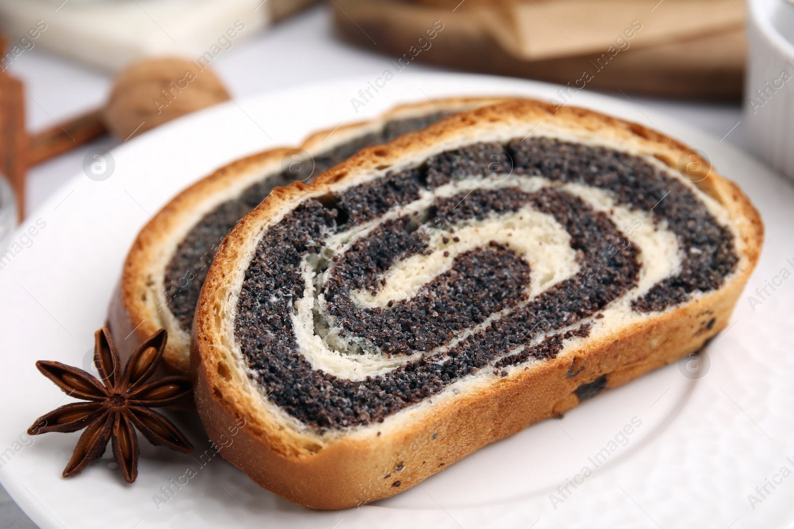 Photo of Slices of poppy seed roll and anise star on plate, closeup. Tasty cake