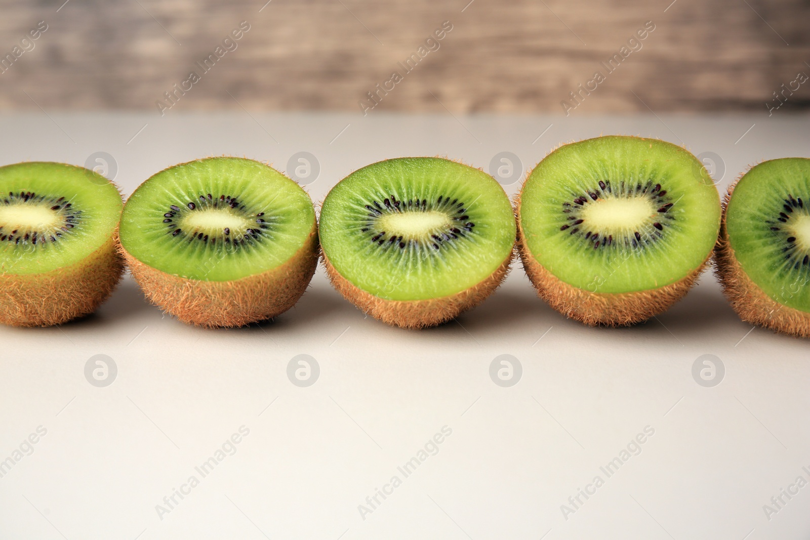 Photo of Halves of fresh kiwis on beige background