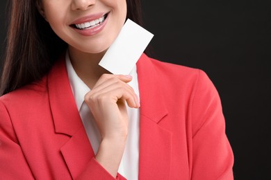 Woman holding blank business card on black background, closeup. Space for text