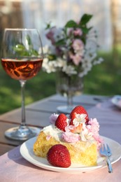 Photo of Glass of wine and cake on table served for romantic date in garden