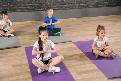 Cute little children sitting on floor and doing physical exercise in school gym. Healthy lifestyle