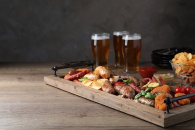 Set of different tasty snacks and beer on wooden table, space for text