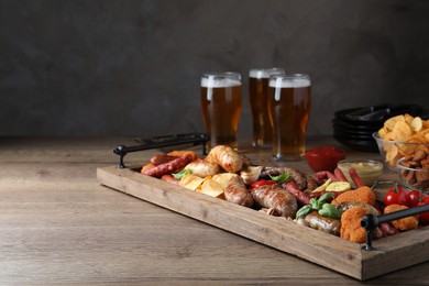 Photo of Set of different tasty snacks and beer on wooden table, space for text