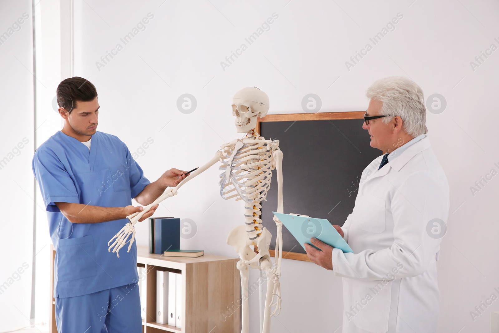 Photo of Medical student and professor studying human skeleton anatomy in classroom