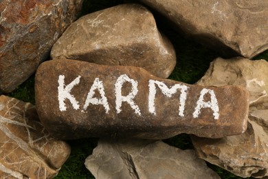 Photo of Stone with word Karma on green grass, above view